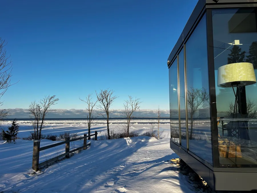 Looking out from inside a Signature across snow and a fence to the sea