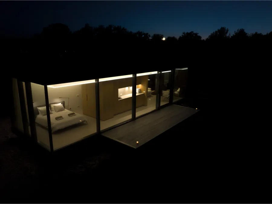 Signature at night, the bed and living room visible through the glass