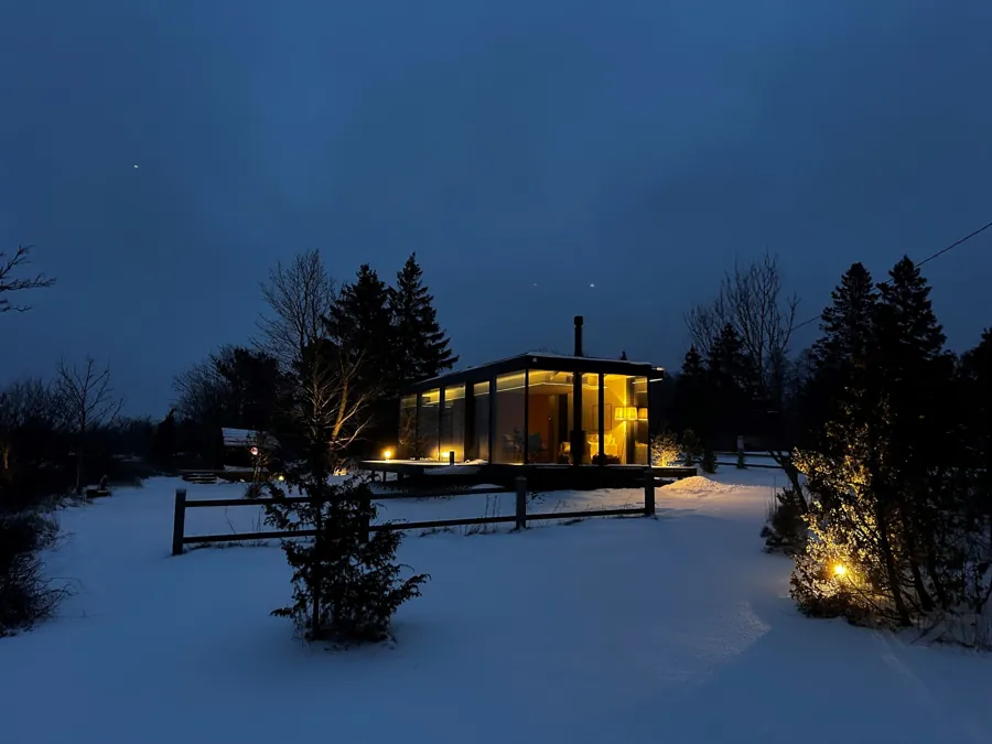 Signature at blue hour in snow, its interior lit warm, path lights in the foreground