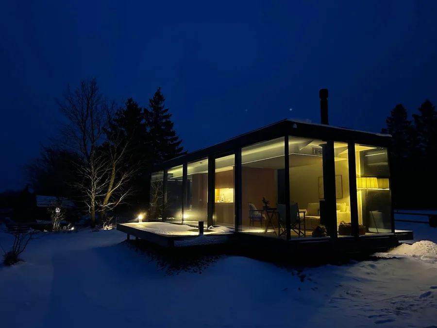 Signature glass house illuminated against the deep blue evening sky