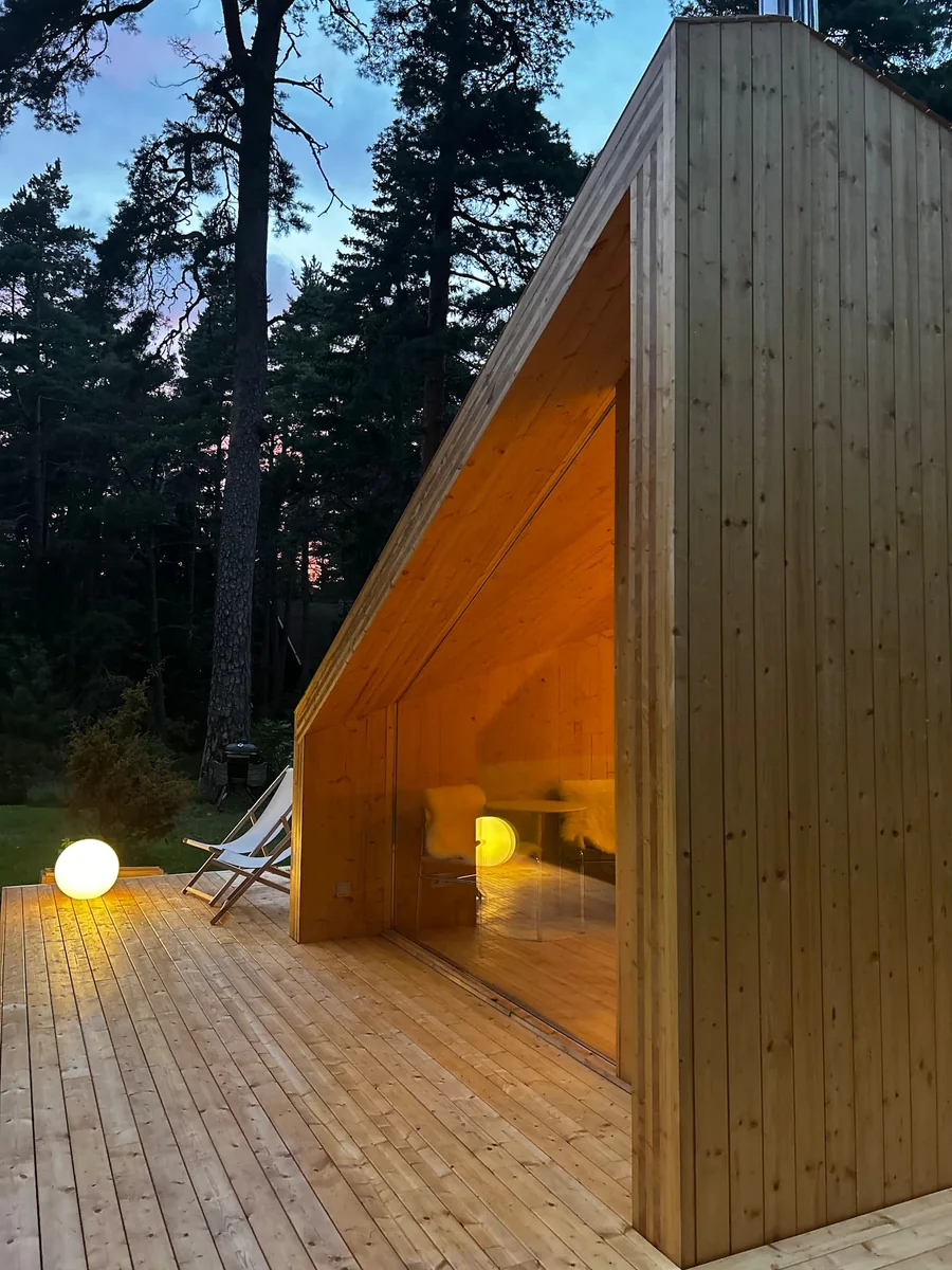 Real Etnika Zen exterior with its folded timber roof, glazed gable and terrace at dusk