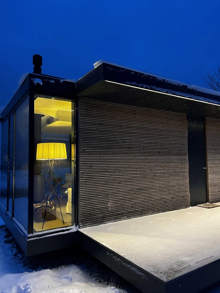 Close view of a Signature's dark timber end at night, a lamp glowing inside