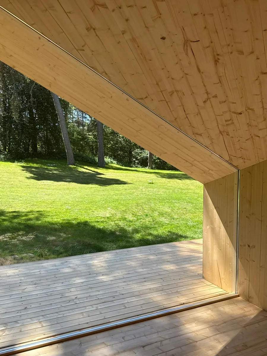 Close view of Zen's folded timber roof edge and deck, lawn and trees behind